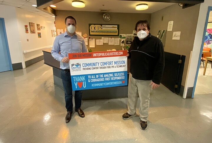 Men holding up "Community Comfort Mission" sign